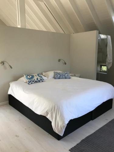 a bedroom with a large white bed with blue pillows at St Francis Cottage close to beach in St Francis Bay