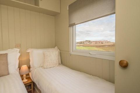 Estuary View Caravans في آلنماوث: غرفة نوم صغيرة بسريرين ونافذة