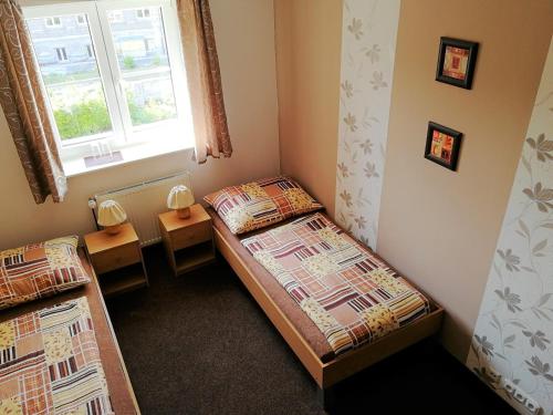 2 Betten in einem kleinen Zimmer mit Fenster in der Unterkunft Vzdělávací Středisko a Hotel in Varnsdorf
