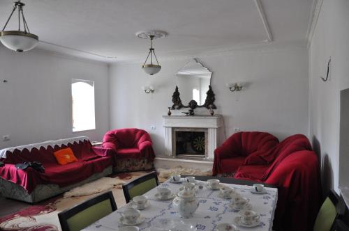 a living room with red couches and a table and a fireplace at Bujtina Gjana in Kukës