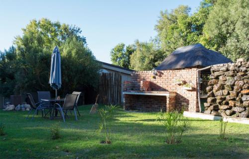a patio with an umbrella and a table and a stone wall at Riverbush Lodge Guesthouse in Parys