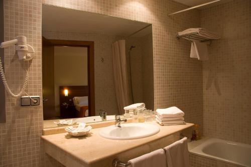 a bathroom with a sink and a mirror and a tub at Hotel Torre Monreal in Tudela