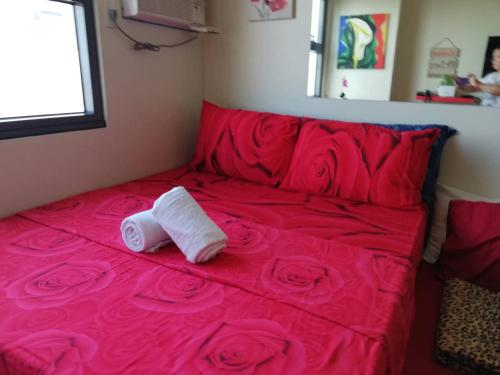 a red bed with two rolled towels on it at Nica's Place Property Management Services at Horizons 101 Condominium in Cebu City