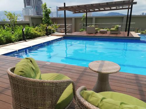 a swimming pool with chairs and a table next to a building at Nica's Place Property Management Services at Horizons 101 Condominium in Cebu City