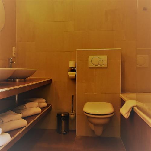 a bathroom with a toilet and a sink and towels at Hotel Courage Nijmegen in Nijmegen