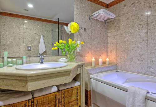 a bathroom with a tub, sink, and mirror at Apollonia Beach Resort & Spa in Amoudara Herakliou