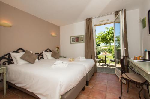 1 dormitorio con cama, escritorio y ventana en Best Western Hôtel Aurélia, en Maussane-les-Alpilles