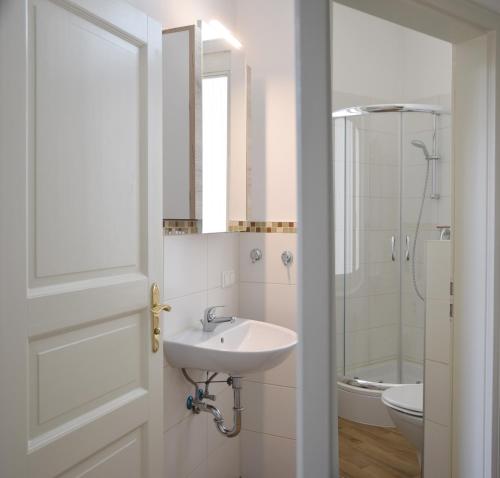 a white bathroom with a sink and a mirror at Zur Eiche Potsdam in Potsdam