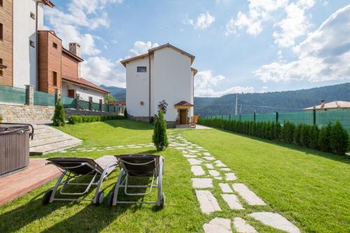a garden with two chairs on the grass at Villa ADELHEIDE - Spa, BBQ & Jacuzzi in Beli Iskar