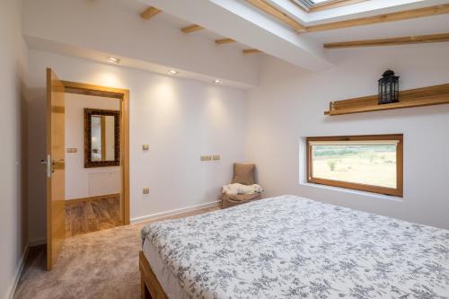 a white bedroom with a bed and a window at Villa ADELHEIDE - Spa, BBQ & Jacuzzi in Beli Iskar