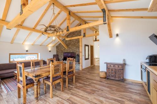 a dining room and living room with a wooden table and chairs at Villa ADELHEIDE - Spa, BBQ & Jacuzzi in Beli Iskar