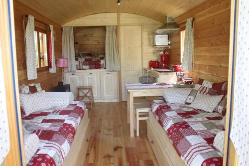 um quarto com duas camas e uma cozinha num camarote em les roulottes de dilou Cerise em Matha