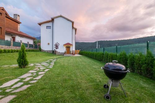 a bbq grill in a yard next to a building at Villa ADELHEIDE - Spa, BBQ & Jacuzzi in Beli Iskar