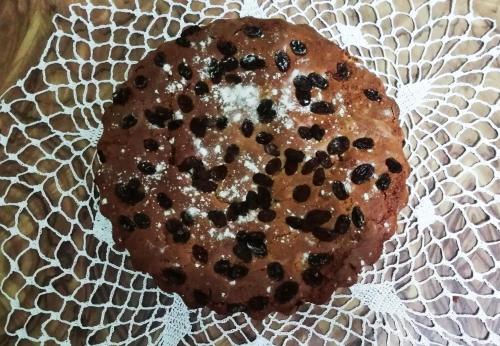 a cake with raisins on a white paper plate at Guesthouse Belle View Old Town in Berat
