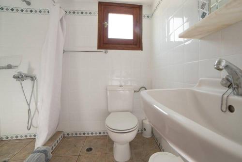 a white bathroom with a toilet and a bath tub at Nicolas Pension in Skiros