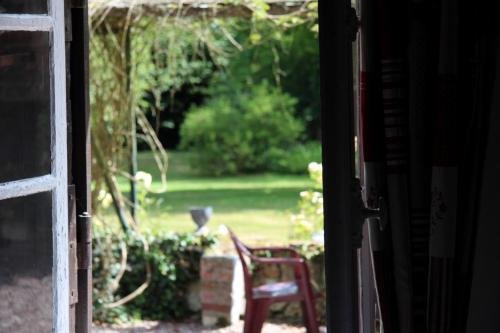 an open door with a chair in a yard at Le Pommenial de la Hérissonnière in Saint-Aubin-de-Bonneval