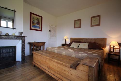 1 dormitorio con cama de madera y chimenea en Le Pommenial de la Hérissonnière, en Saint-Aubin-de-Bonneval