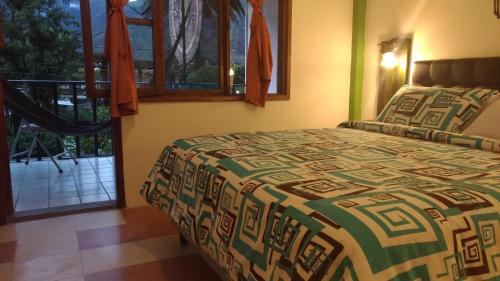 a bedroom with a bed and a view of a balcony at Hostal & Spa Casa Real in Baños