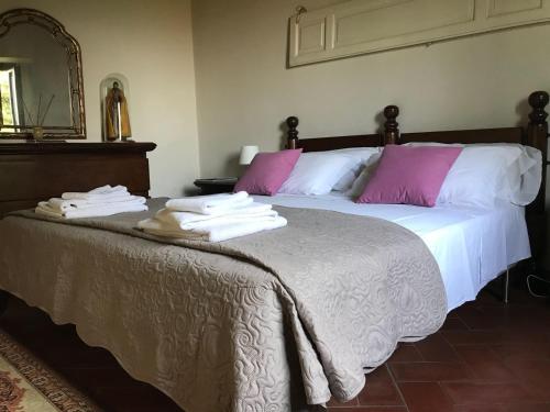 a bedroom with a large bed with pink and white pillows at Podere Belvedere - Villa with private swimming-pool in Carmignano
