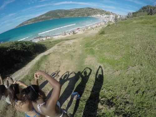 a woman standing on a hill next to a beach at Praia Grande Arraial do Cabo in Arraial do Cabo