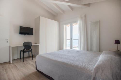 a white bedroom with a bed and a window at Terrazze sul Garda in Tenno