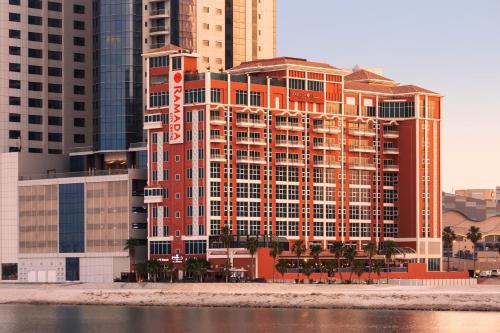 Ramada by Wyndham Manama City Centre في المنامة: مبنى كبير على الشاطئ مع مباني طويلة