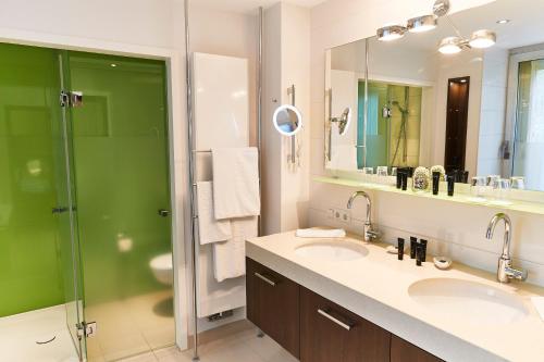 a bathroom with two sinks and a shower at Steigenberger Airport Hotel Frankfurt in Frankfurt/Main