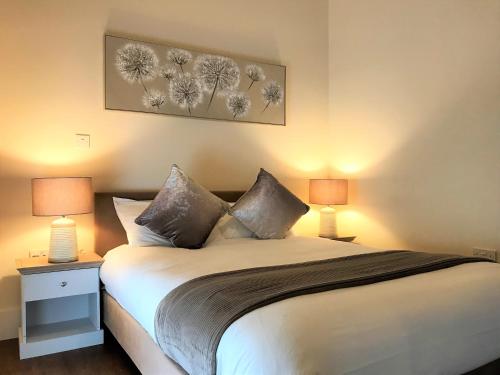 a bedroom with a bed with two lamps on it at Ice House Apartments in Swansea