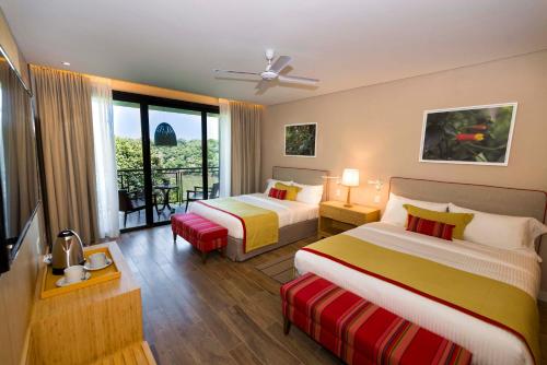 um quarto de hotel com duas camas e uma varanda em Iguazu Jungle Lodge em Porto Iguaçu