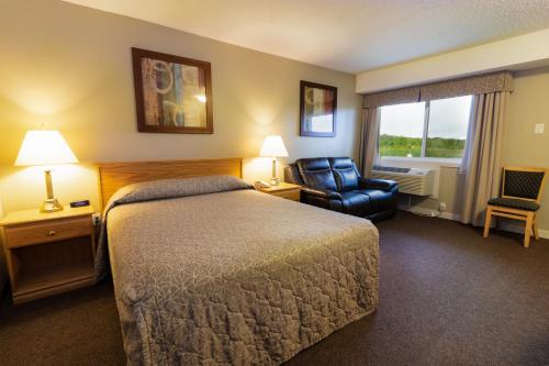 um quarto de hotel com uma cama e uma cadeira em BCMInns - Lloydminster em Lloydminster