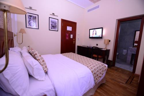 a bedroom with a bed and a desk and a television at Grand Hotel Villa de France in Tangier