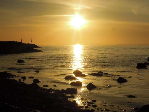 a sunset over the ocean with rocks on the shore at Panorama Hotel Lohme in Lohme