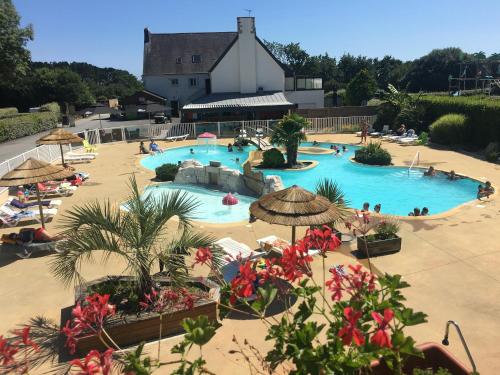 a large swimming pool with umbrellas and people at a resort at Camping Kost Ar Moor in Fouesnant