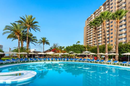 a large swimming pool with chairs and umbrellas at Sol Arona Tenerife in Los Cristianos