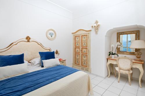 a white bedroom with a bed and a desk at Hotel Onda Verde in Praiano