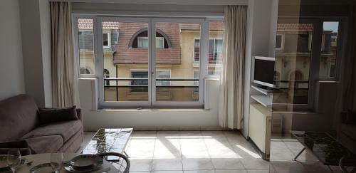 a living room with a couch and a large window at Studio Casinoplein Middelkerke in Middelkerke
