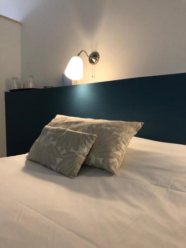 a bed with a pillow and a lamp on it at La Basse Cour in Tanlay