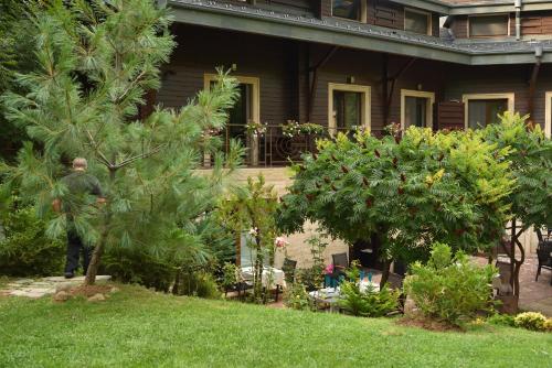 a man standing in the yard of a house with trees at Vila 6aTo Hotel & Wellnes in Sofia