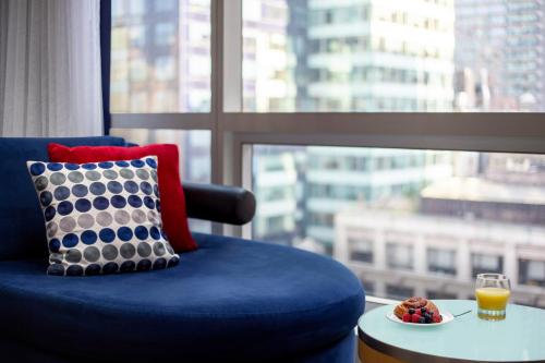 a blue chair with a bowl of fruit on a table next to a window at Millennium Premier New York Times Square in New York