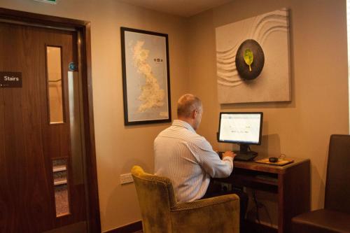 a man sitting at a desk in front of a computer at Best Western Pontypool Metro Hotel in Pontypool