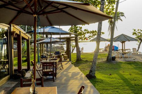 a wooden deck with tables and umbrellas on the beach at Aldeia do Mar Sensorial Hotel in Itacaré