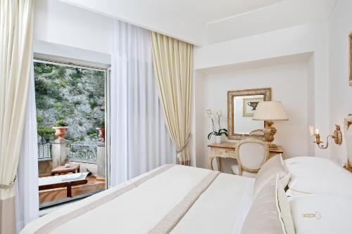 a white bedroom with a bed and a balcony at Hotel Onda Verde in Praiano