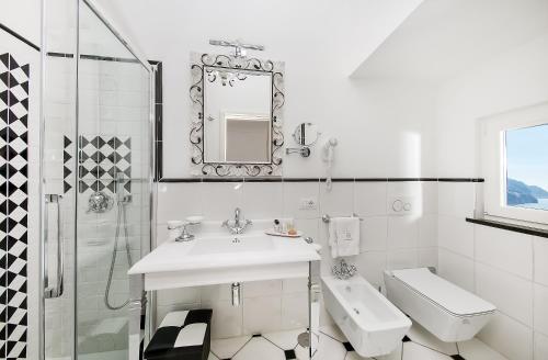a white bathroom with a sink and a toilet at Hotel Onda Verde in Praiano