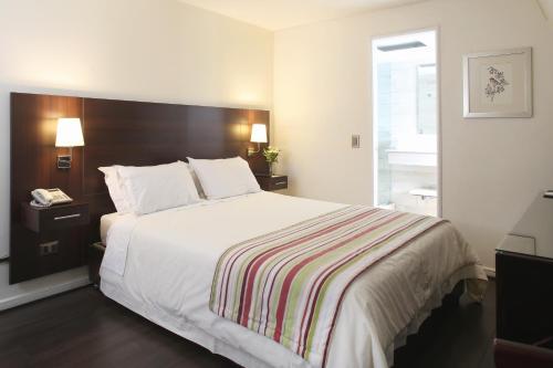a bedroom with a large bed with a striped blanket at MR Express (ex Hotel Neruda Express) in Santiago