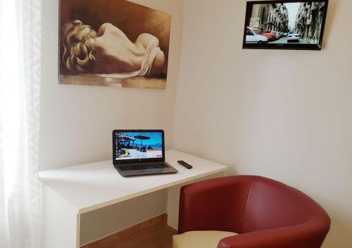 a laptop computer sitting on a white desk with a red chair at Cristal Rooms in Piacenza
