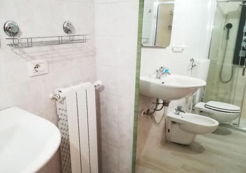 a white bathroom with a sink and a toilet at Cristal Rooms in Piacenza