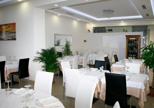 a dining room with white tables and white chairs at Cristal Rooms in Piacenza