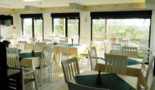 ein Esszimmer mit Tischen, Stühlen und Fenstern in der Unterkunft Green Coffee House in Sulina