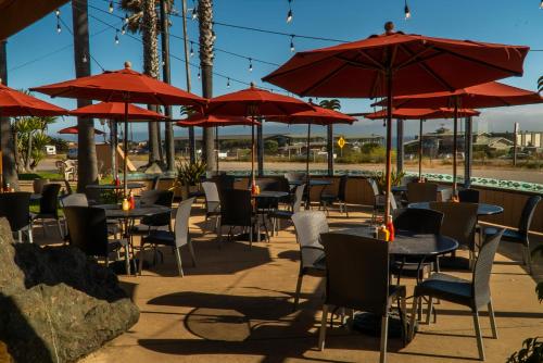 a restaurant with tables and chairs with red umbrellas at San Simeon Lodge in San Simeon