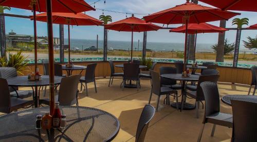 a restaurant with tables and chairs and red umbrellas at San Simeon Lodge in San Simeon
